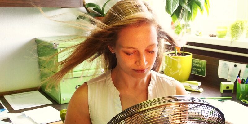 hot-summer-in-the-office-cooling-down-with-a-fan-GLHTBY9 (1)